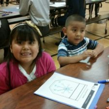 Two students sitting at a cafeteria table working on a financial literacy activity.
